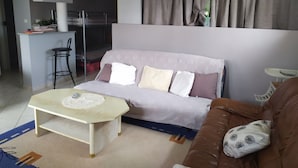 A living room with a sofa, a coffee table, a dining area with a bar, and a kitchen in the background. - rental in the heart of gerardmer (Gérardmer)
