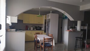 A compact kitchen with a dining area, featuring a table with chairs, a microwave, and a refrigerator. - rental in the heart of gerardmer (Gérardmer)