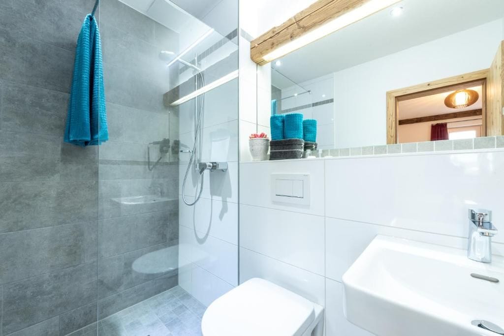 A modern bathroom with a glass shower enclosure, a white sink, and a visible towel rack.