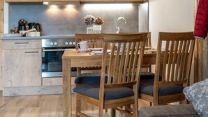 Una mesa de comedor de madera con dos sillas, una cocina con armarios de madera, una estufa y un lavamanos.