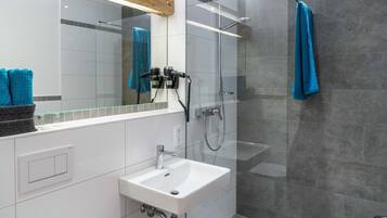 Une salle de bain moderne avec une douche à parois de verre, un lavabo blanc et un miroir au-dessus du lavabo.