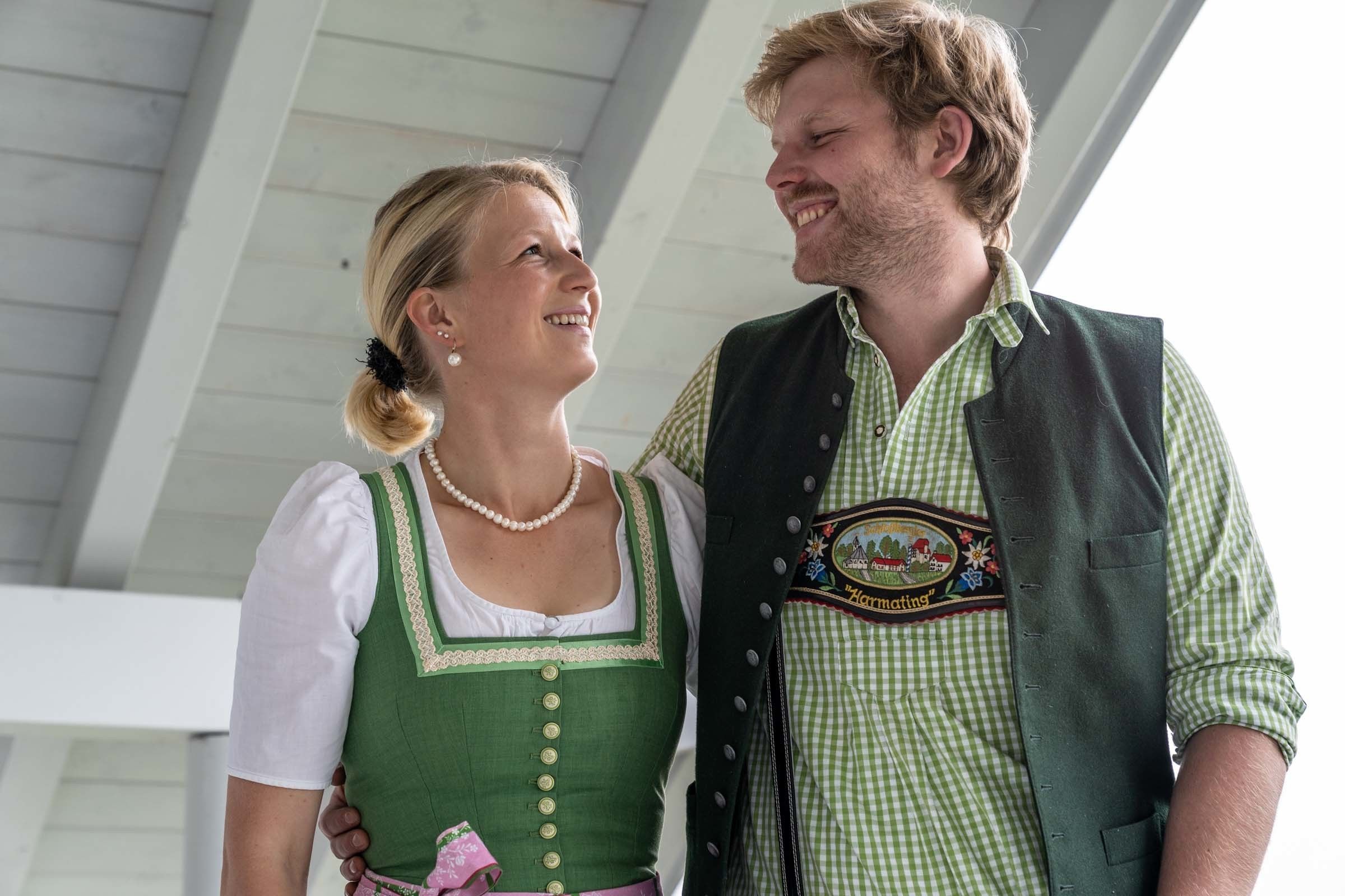 A couple dressed in traditional attire, standing under a roofed structure.