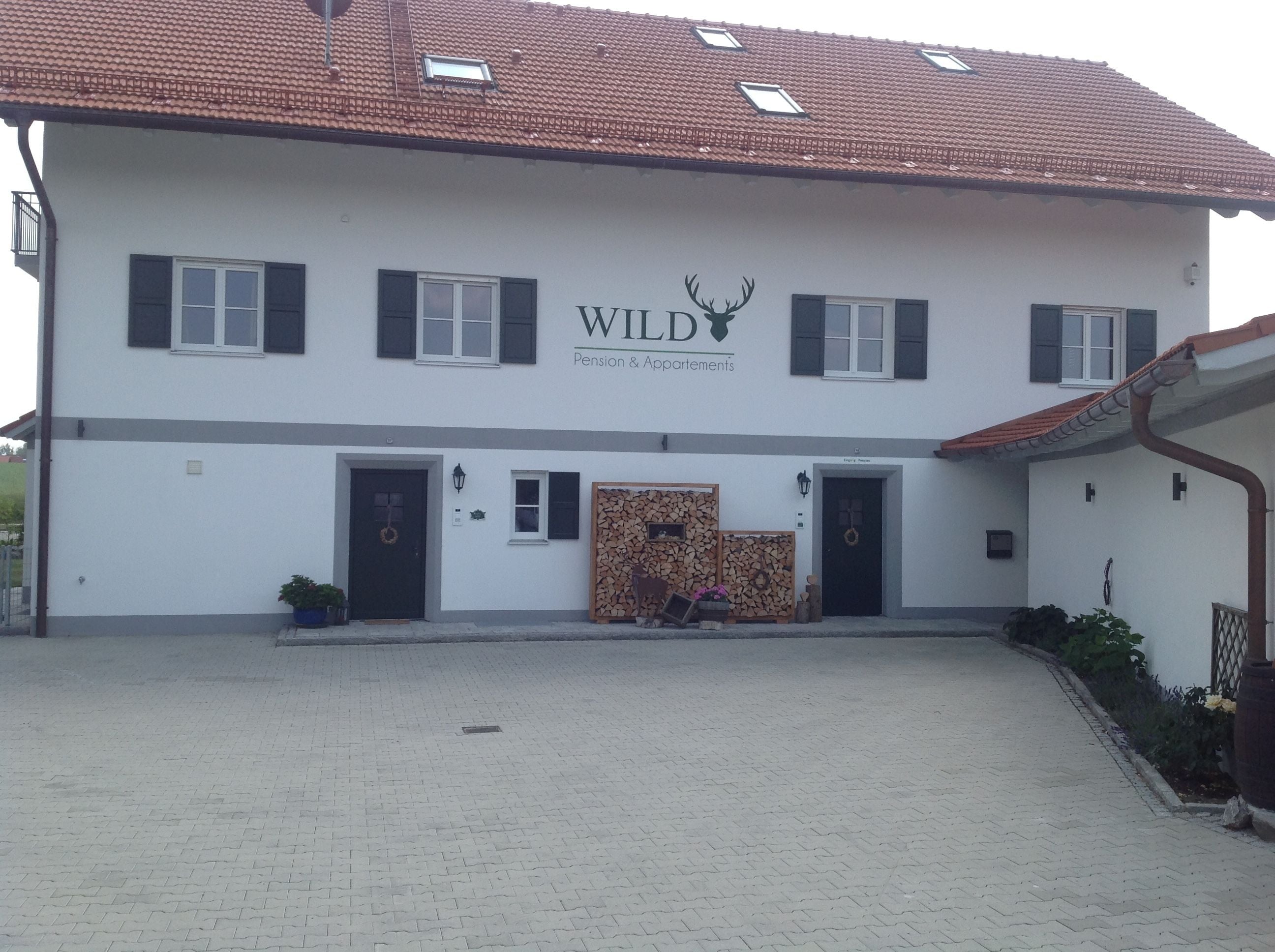 Un edificio de dos plantas con un cartel que dice 'WILD Pension Apartments'.