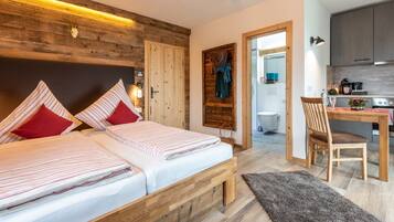 A bedroom with two beds, a wooden headboard, a small desk, and a chair.