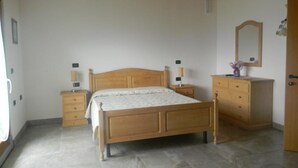 Ein Schlafzimmer mit einem hölzernen Bett, Nachttischen, einer Kommode und einem Spiegel an der Wand.