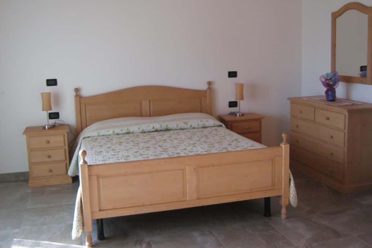 A bedroom with a wooden bed, two bedside tables, a dresser, and a mirror.