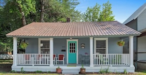 A single-story house with a porch, a door, and a small table with chairs.
