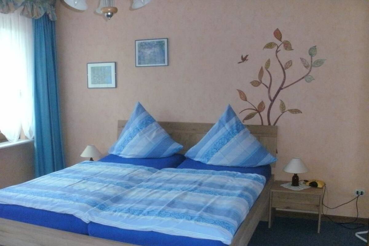 A bedroom with a bed, two bedside tables, and a wall decoration.