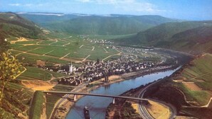 A town with a river, surrounded by green hills, and a bridge crossing the river. - Gästehaus Andrae (Bruttig-Fankel)