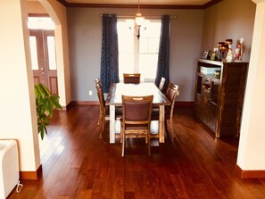 Enjoy meals in this cozy dining area with a wooden table and chairs, a chandelier, and a cabinet.