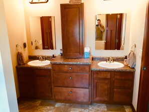 Two sinks with separate vanities and ample storage in a clean and modern bathroom.