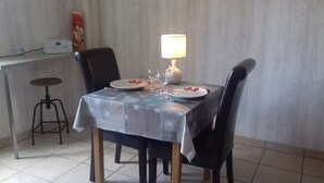 Een eethoek met een gedekte tafel voor twee personen, een lamp en een decoratieve vaas.
