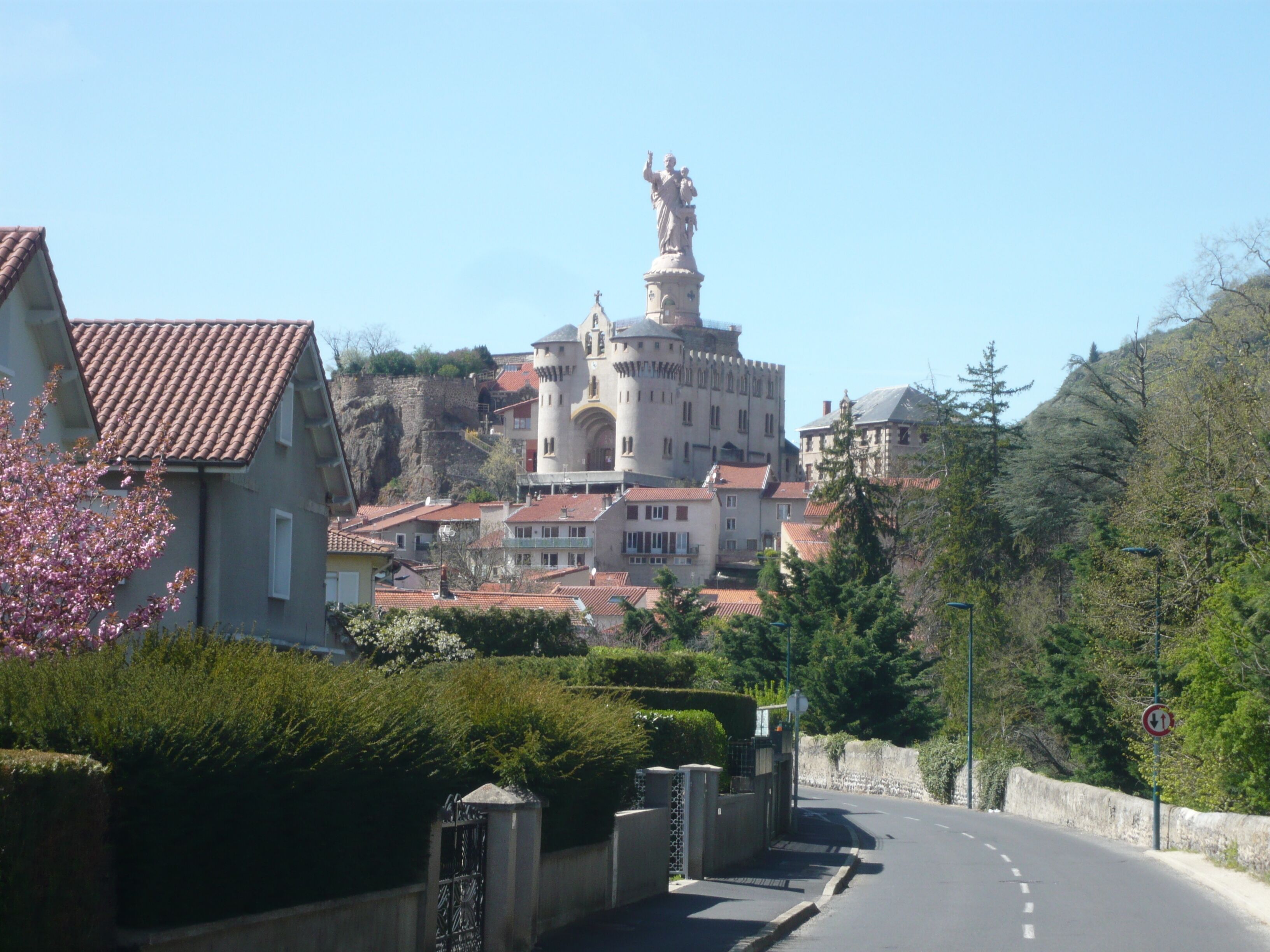 Un château surmonté d’une statue, entouré d’immeubles résidentiels et de verdure.