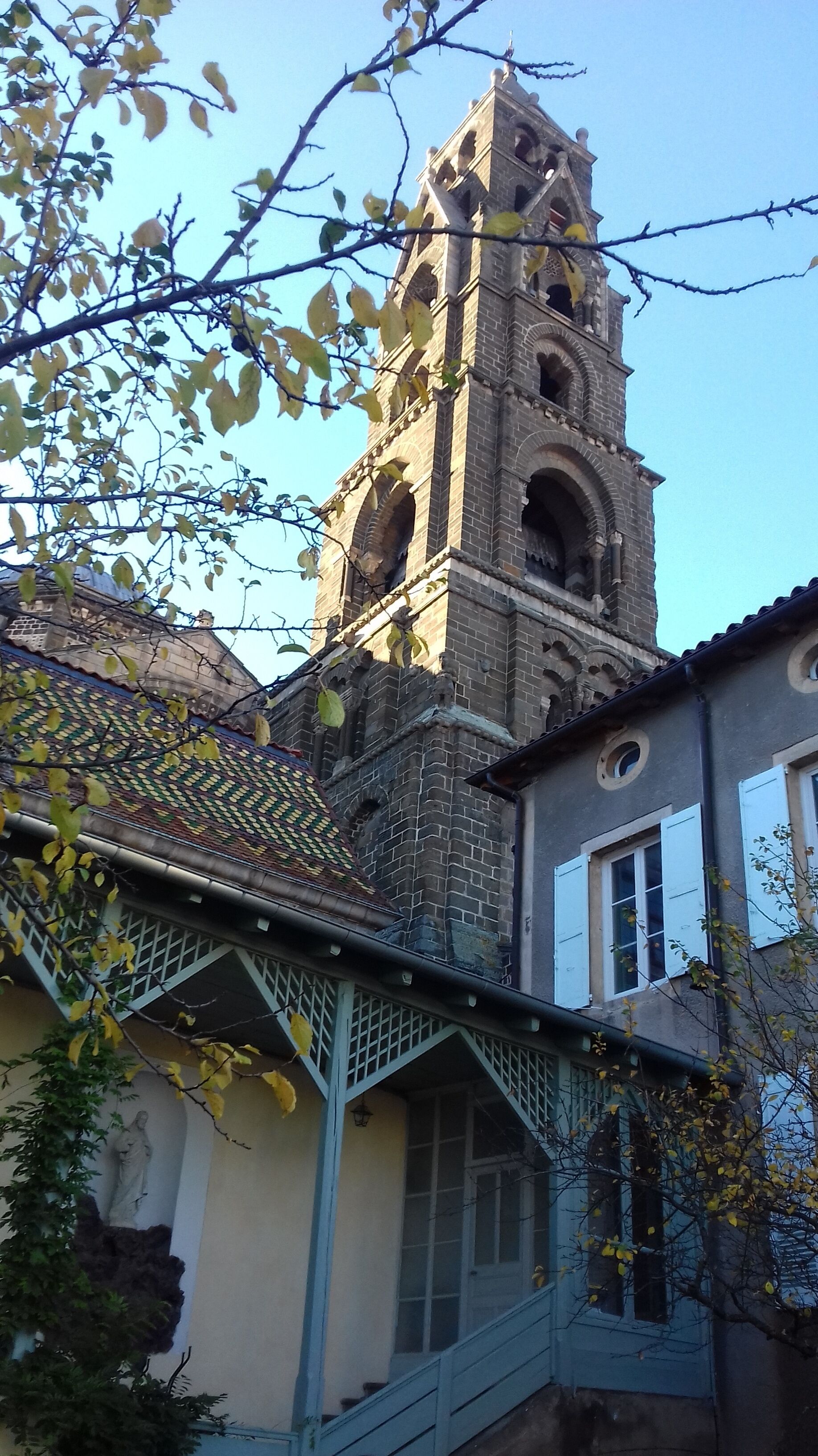 Un edificio storico con una torre imponente, un balcone con ringhiera e una statua sulla parete.