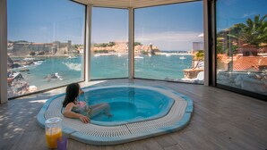 A child in a hot tub with a view of a coastal town and boats. - Le Relais des trois Mas (Collioure)