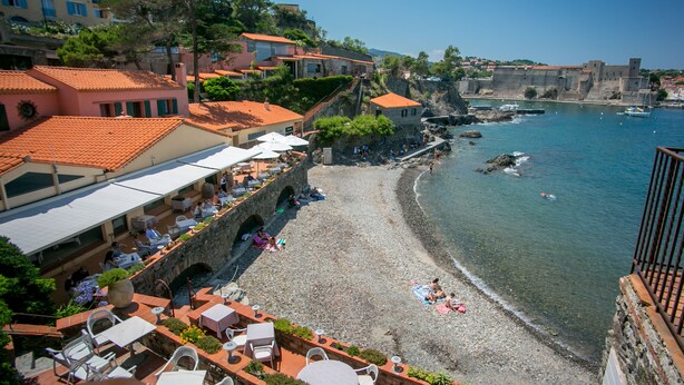 A coastal hotel with outdoor seating, a stone wall, and a view of the sea. - Le Relais des trois Mas (Collioure)