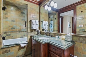 Een bad/douchecombinatie, een bubbelbad, een haardroger, handdoeken