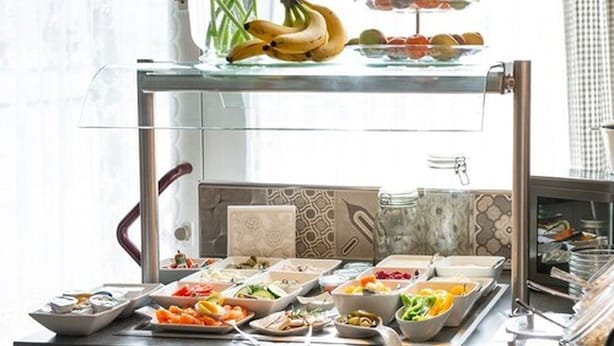 A buffet setup with various food items and a vase of red tulips. - City Hotel (Geilenkirchen)