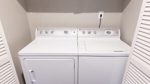 Una sala de lavandería con dos lavadoras blancas de carga frontal y una secadora.