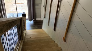 Una escalera de madera con barandilla que conduce a una habitación con paredes blancas y suelo de madera.