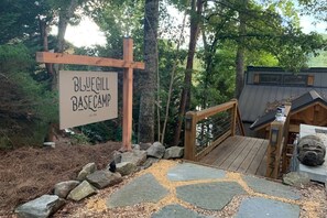 Un letrero de madera para Blue Gill Base Camp, con un camino de piedra que conduce a una estructura de madera.