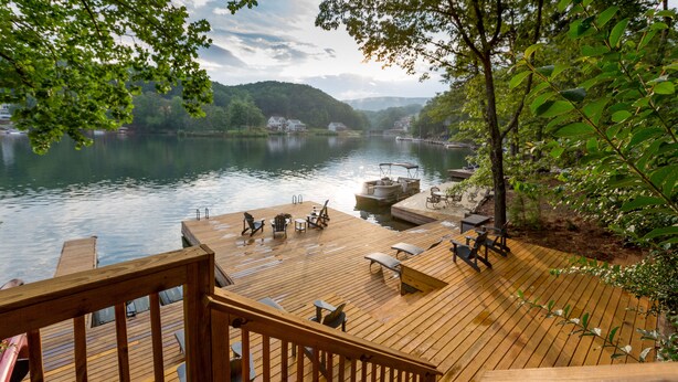 Una terraza de madera con mobiliario exterior y vista al río.