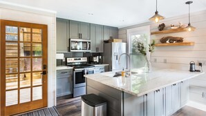 Una cocina moderna con armarios grises, electrodomésticos de acero inoxidable y encimera de mármol.