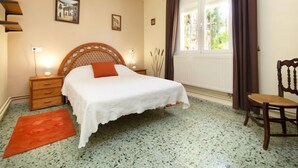 A bedroom with a bed, a chair, a nightstand, a window with curtains, and a radiator. - Vacation home Alma by Interhome (Calpe/Calp)