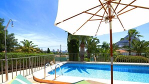 A pool area with lounge chairs and a large umbrella. - Vacation home Alma by Interhome (Calpe/Calp)