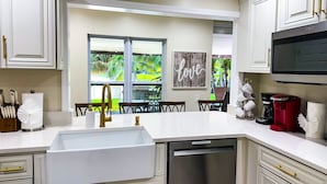 A modern kitchen with white cabinetry, a stainless steel dishwasher, and a coffee maker.