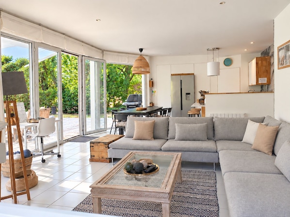 A spacious living area with a large sofa, a coffee table, and a dining table.