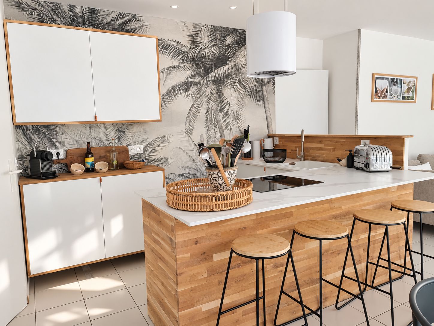 Een moderne keuken met een centraal eiland, barstoelen en een wandlamp.
