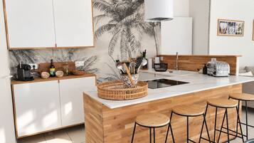 Een moderne keuken met een centraal eiland, barstoelen en een wandlamp.