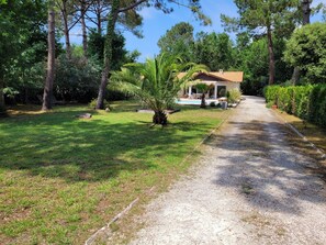 A house with a covered patio, surrounded by a well-maintained lawn and trees.