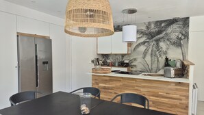Moderni keittiö, jossa on puinen työtaso, roikkuva punottu valaisin ja seinämaalaus, jossa on kuvattuna palmuja.