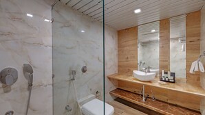 A modern bathroom with a glass-enclosed shower, a white toilet, a vanity with a sink, and a mirror.