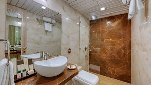 A modern bathroom with a large white sink, a toilet, and a shower area with marble tiles.