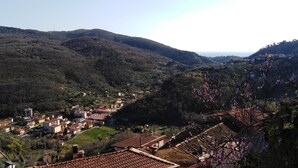 Ein Dorf an einem Hügel mit terrassenförmig angelegten Häusern, einer kleinen Kirche und Blick auf das Meer.