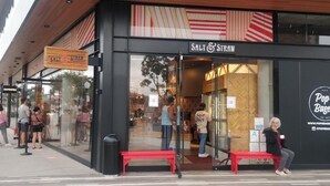Une devanture de magasin avec une enseigne indiquant « Salt & Straw » et un logo pour « Pop's Bagels ».