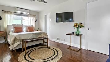 Een slaapkamer met een bed, nachtkastjes, een televisie, een raam en een deur.