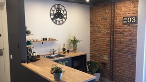 A modern kitchen with a wooden countertop, a black clock, and a brick wall. - La finestra sul porto (Palermo)