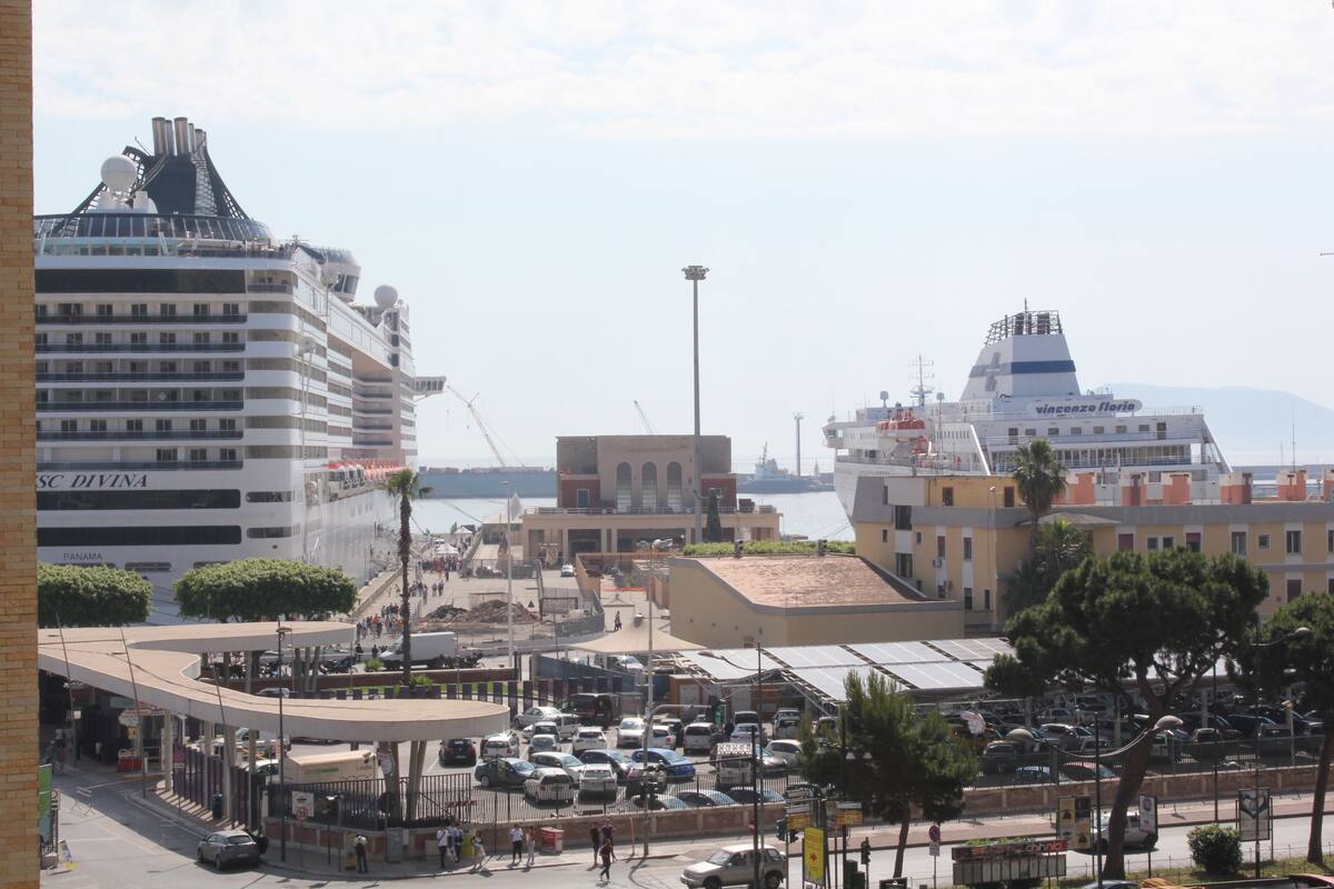 A busy port with cruise ships and a large building labeled "SC DIVINA."