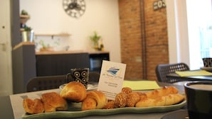 A breakfast setting with croissants and a coffee cup, a business card, and a clock on the wall. - La finestra sul porto (Palermo)
