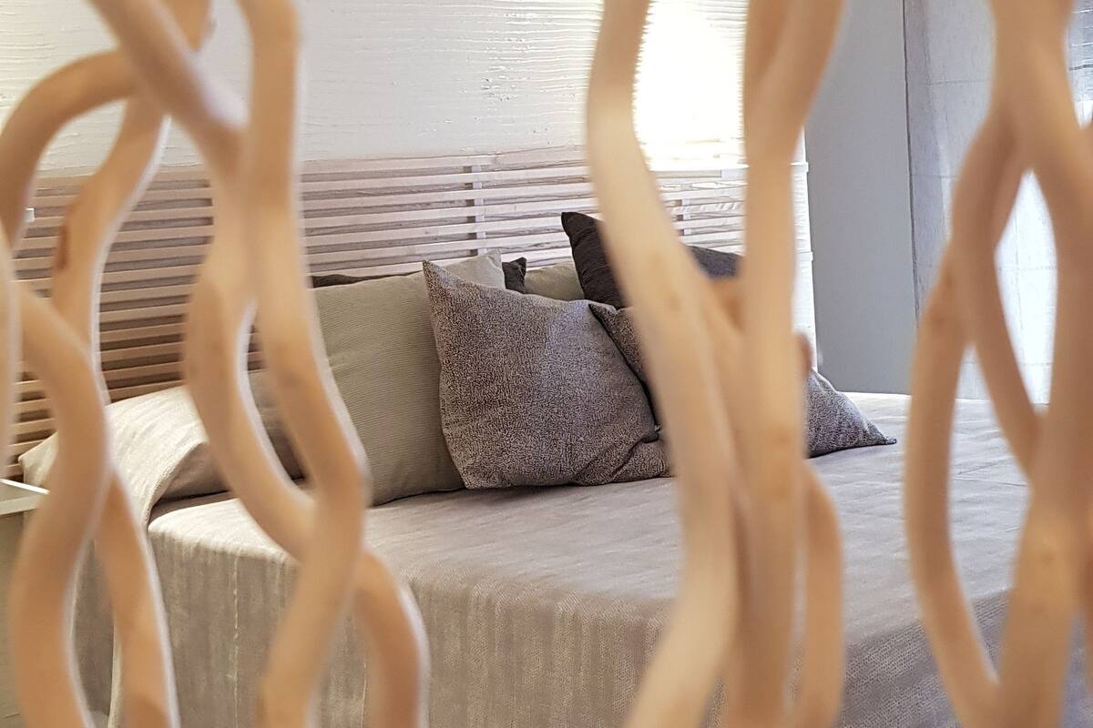 A bedroom with a bed, pillows, and a window.