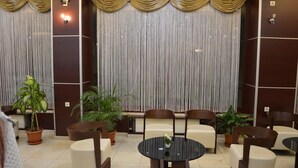 Un hall con una mesa redonda, varias sillas y plantas en macetas.