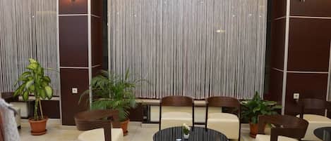 A lobby with a round table, several chairs, and potted plants.