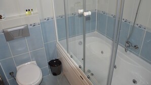 Un baño con ducha envuelta en vidrio, inodoro y lavamanos.