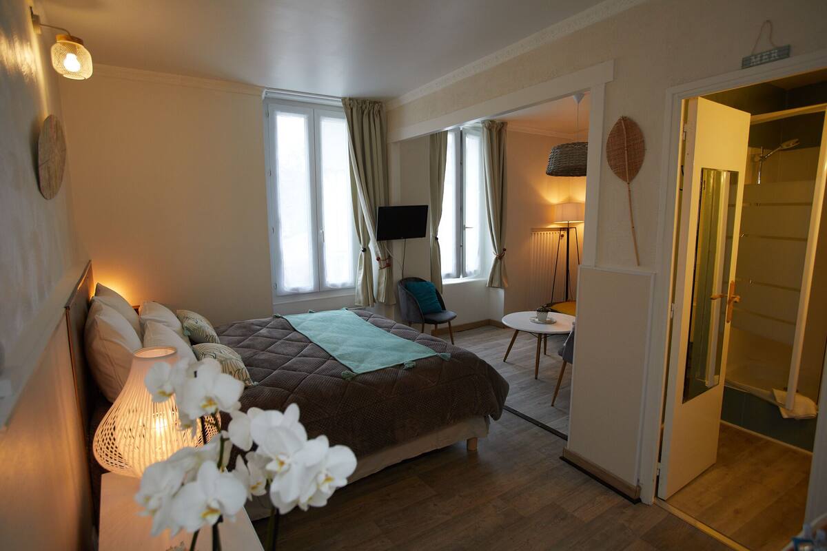 A bedroom with a bed, a desk, and a bathroom.
