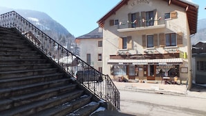 A hotel named Le Doron with a bar and restaurant on the ground floor, a staircase with ornate metal railings, and a mountain backdrop. - Hotel du Doron (Beaufort)