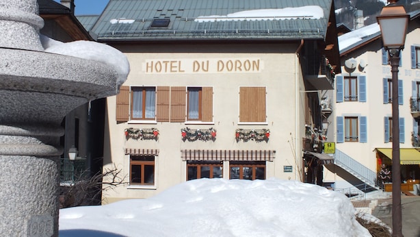 A building labeled "HOTEL DU DORON" with a snow-covered roof and a stone pillar in the foreground. - Hotel du Doron (Beaufort)